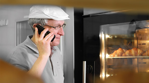 Ein Bäcker beobachtet sein Gebäck im Ofen, während er telefoniert
